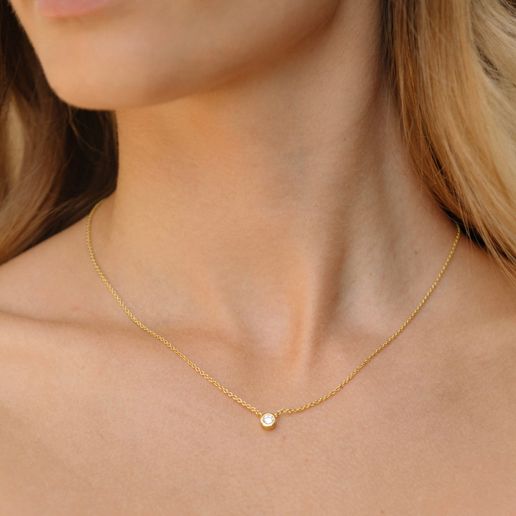 Gold chain necklace with small round bezel-set diamond pendant