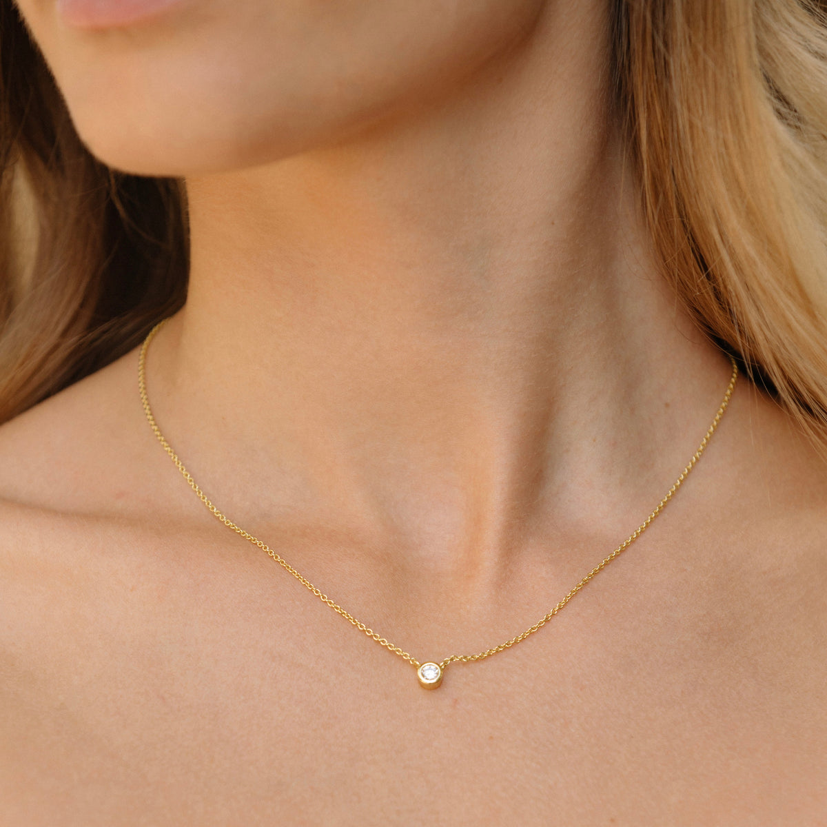 Gold chain necklace with small round bezel-set diamond pendant