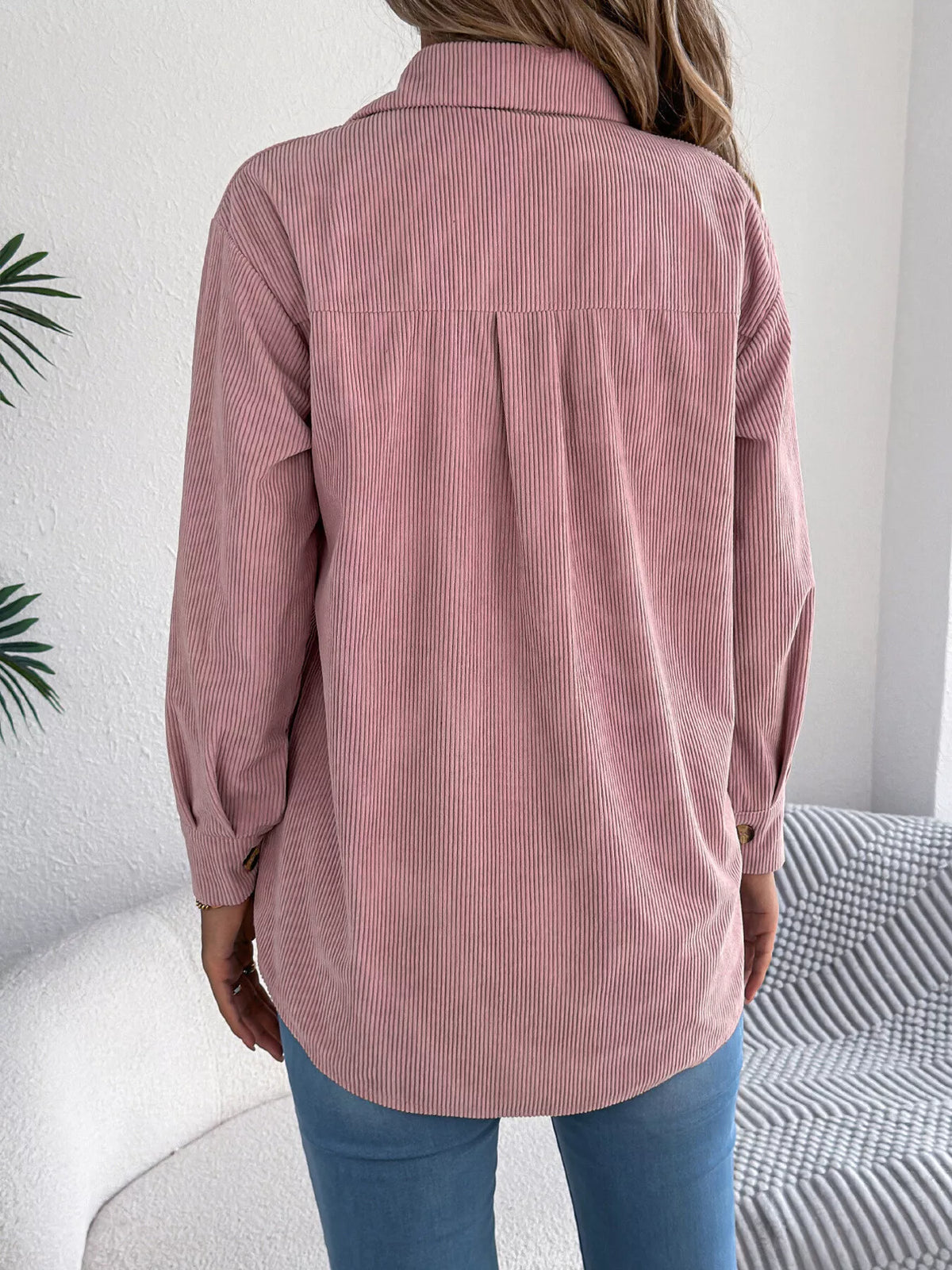 Back view of pink corduroy shacket with curved hem and button cuffs