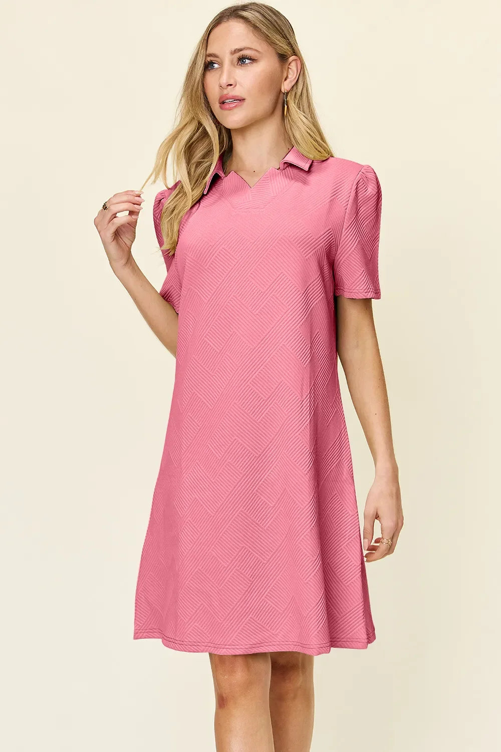 Pink textured collared short-sleeve dress with V neckline, above-knee length.