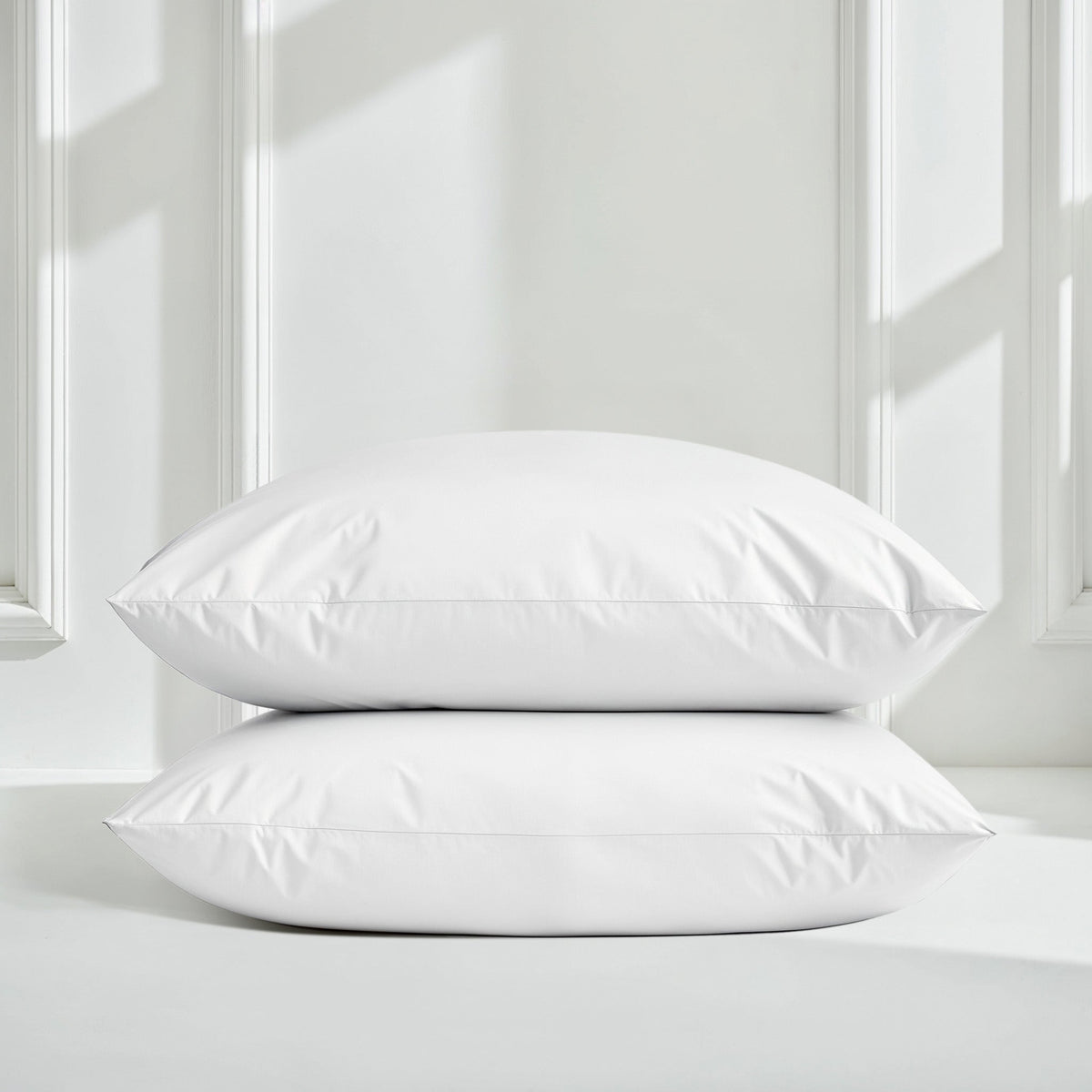 White sateen pillow shams stacked on a bed with matching duvet
