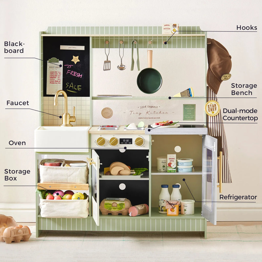 Green kids play kitchen with blackboard panel, faucet, oven, refrigerator, and storage boxes.