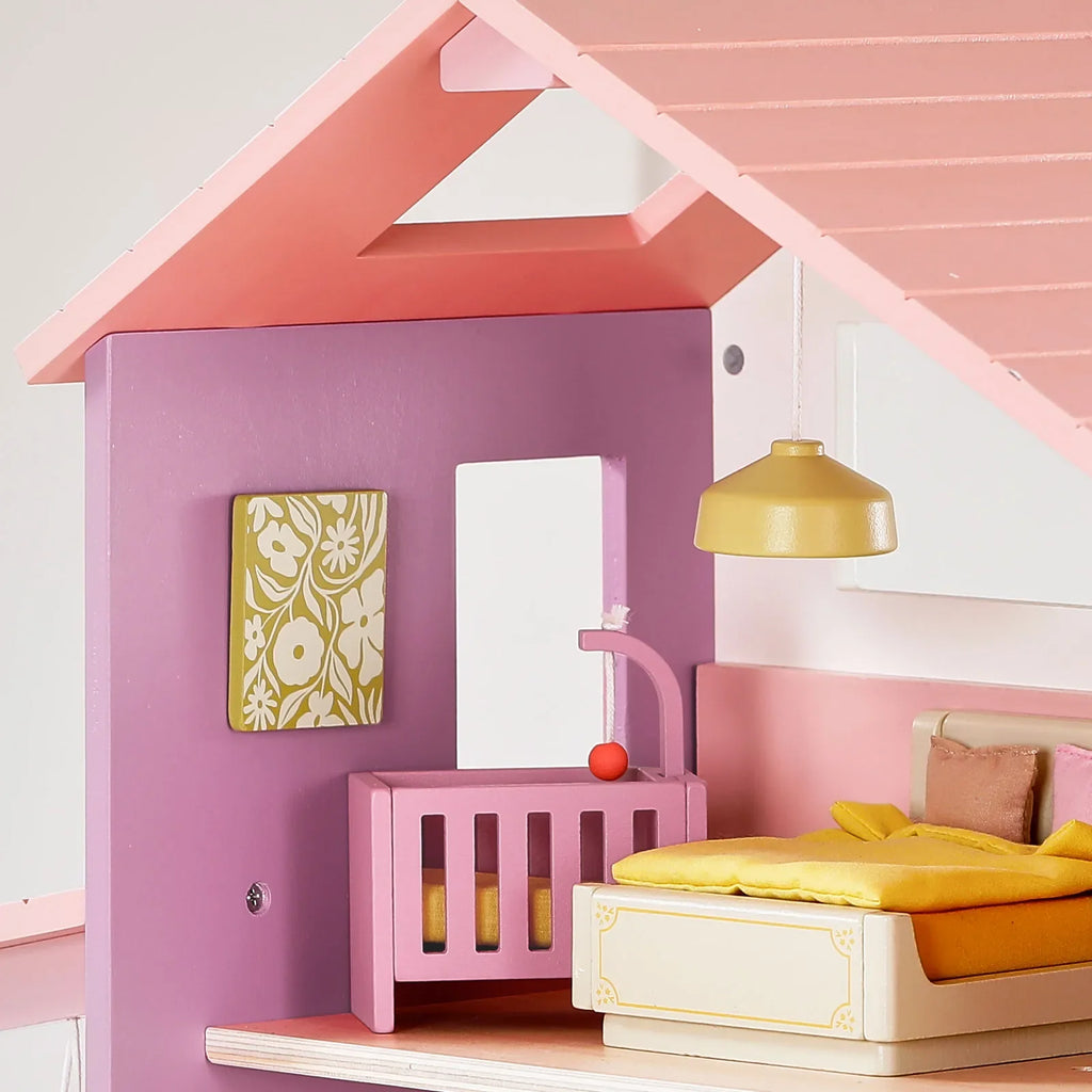 Pink and white dollhouse bedroom with canopy bed and gold hanging light