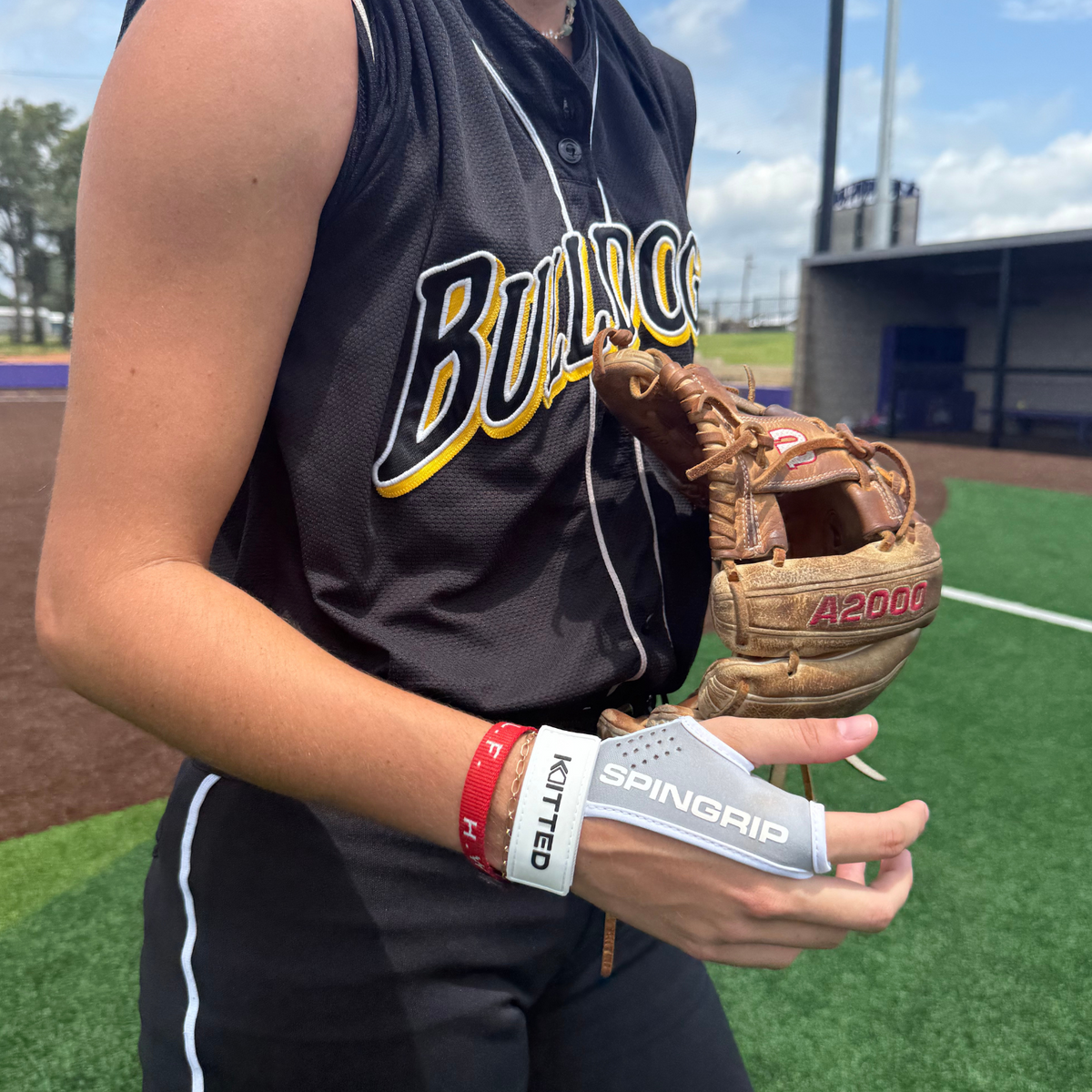 Softball training grip in use holding a neon yellow softball in gray wrist strap