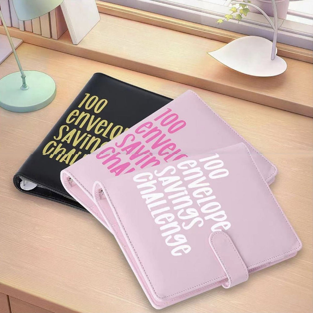 Black and pink envelope savings challenge binders side by side on a tabletop.