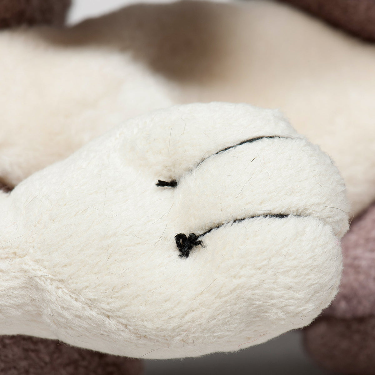 Plush squirrel paw detail with white fabric toe pads and simple black stitching