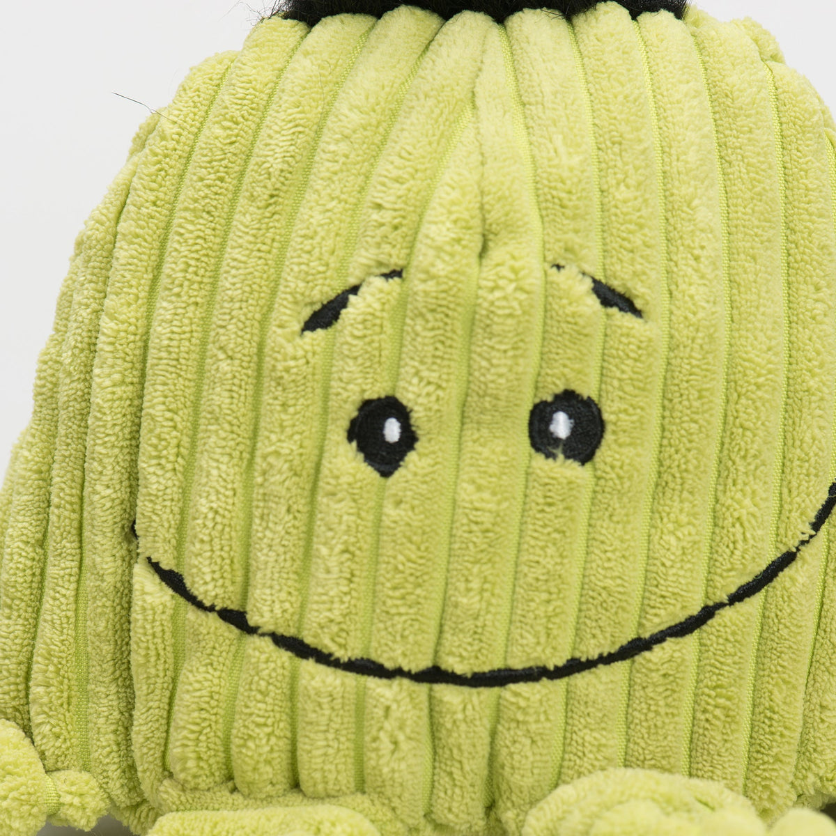 Close-up of lime green plush octopus face with stitched smile and black button eyes