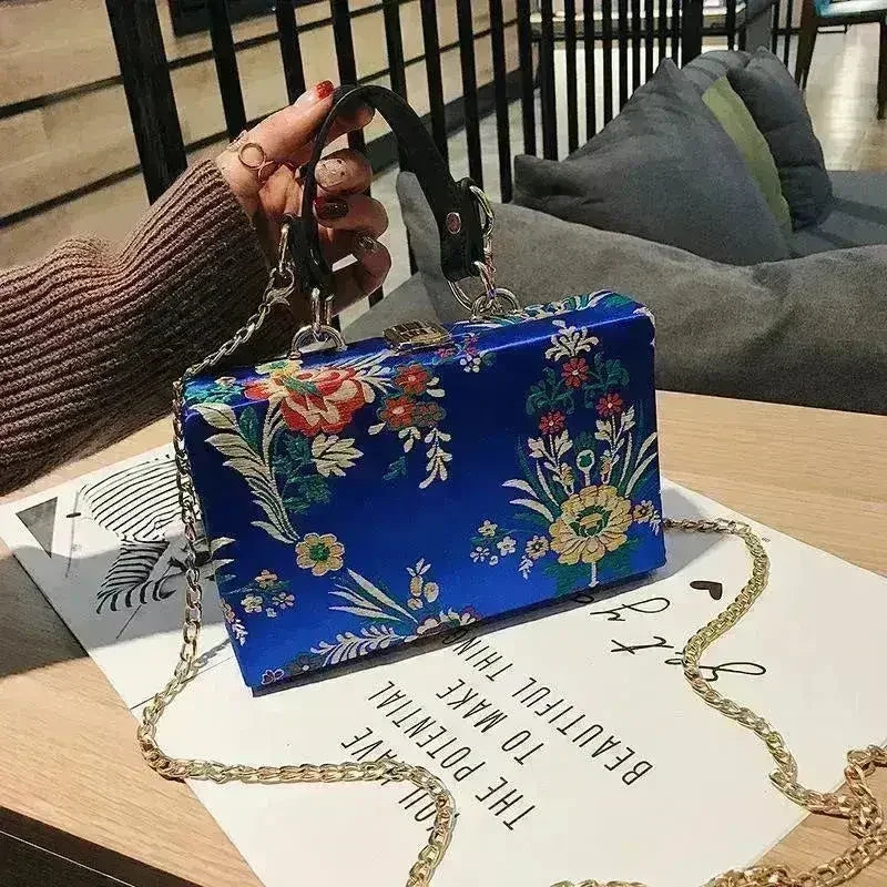 Floral clutch bag in blue with chain strap and colorful botanical print front
