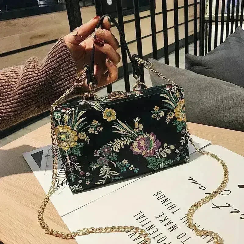 Floral clutch bag in black with colorful botanical print and gold chain shoulder strap