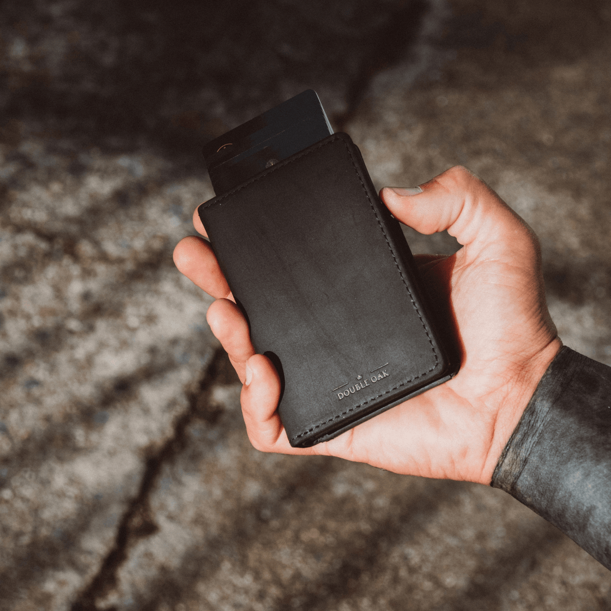 Dark brown bifold wallet with snap closure and leather texture, held in hand.