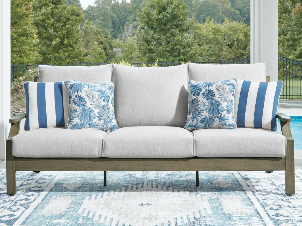 Outdoor sofa with light gray upholstery and two blue floral striped accent pillows