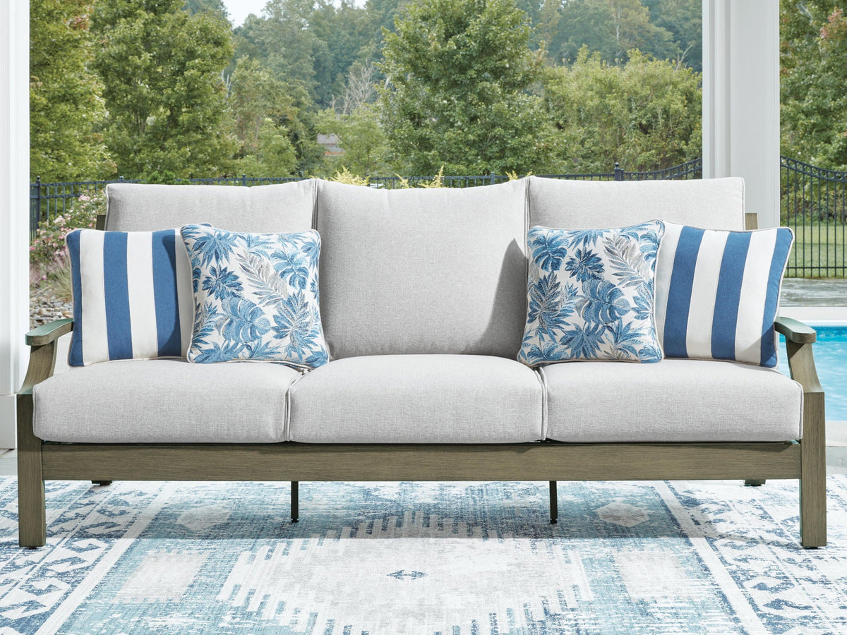 Outdoor sofa with light gray upholstery and two blue floral striped accent pillows