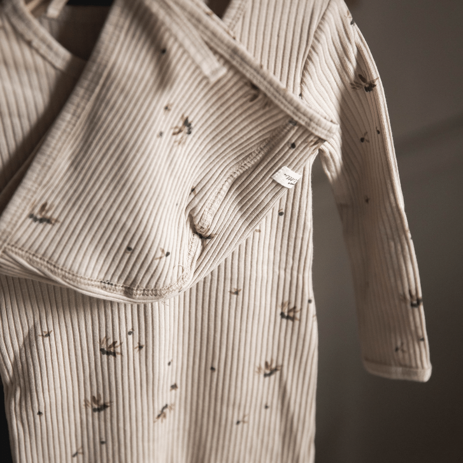 Hooded baby jacket close-up with ribbed stripes and small printed motifs