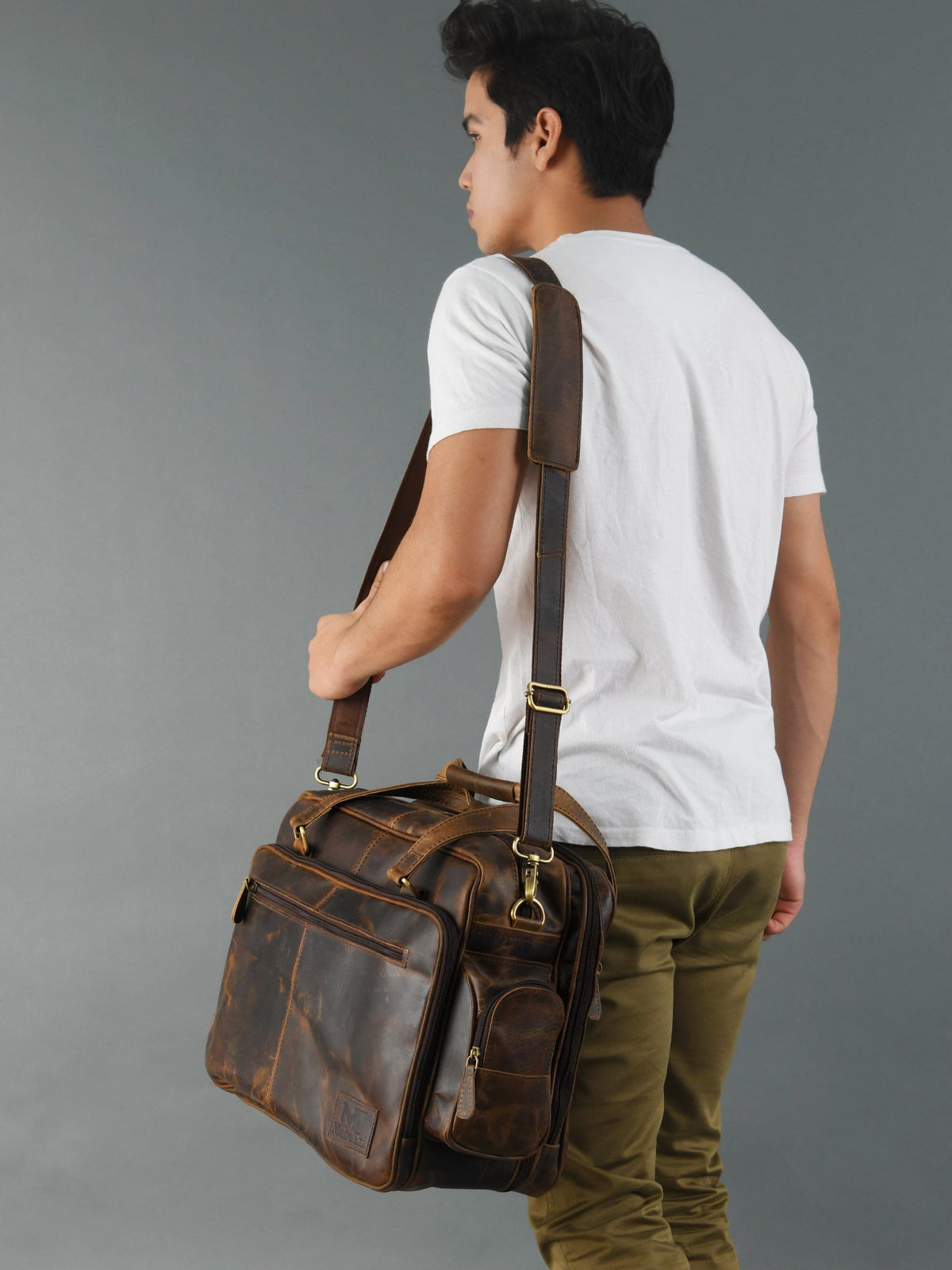 Brown leather briefcase worn on shoulder with crossbody strap and dual top handles
