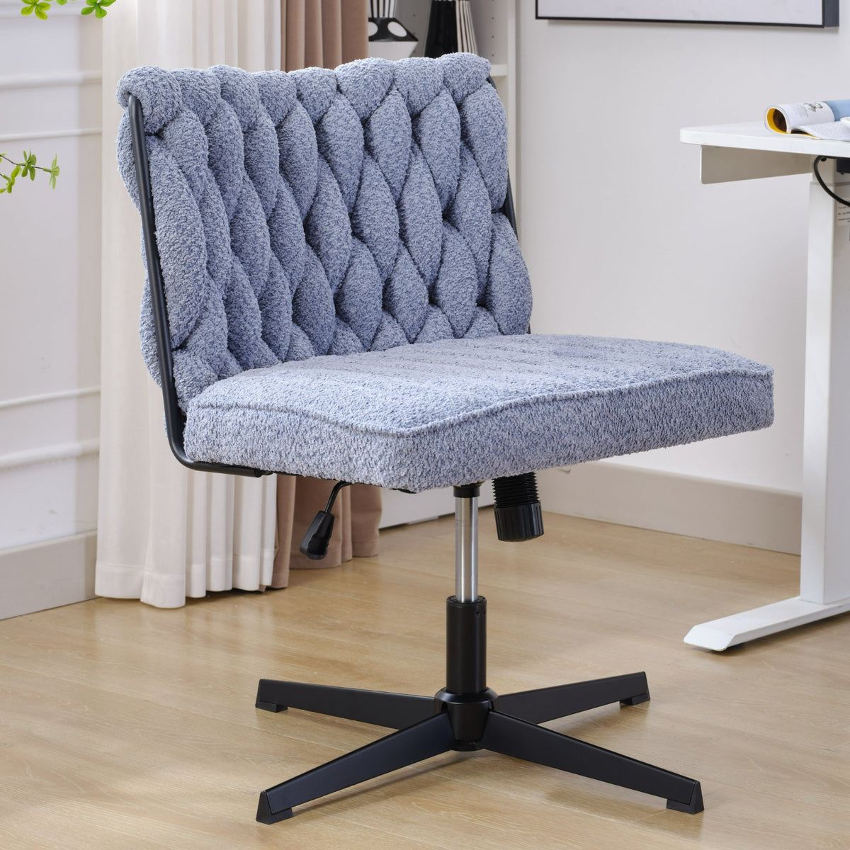 Blue armless desk chair with tufted back and padded seat, black pedestal base