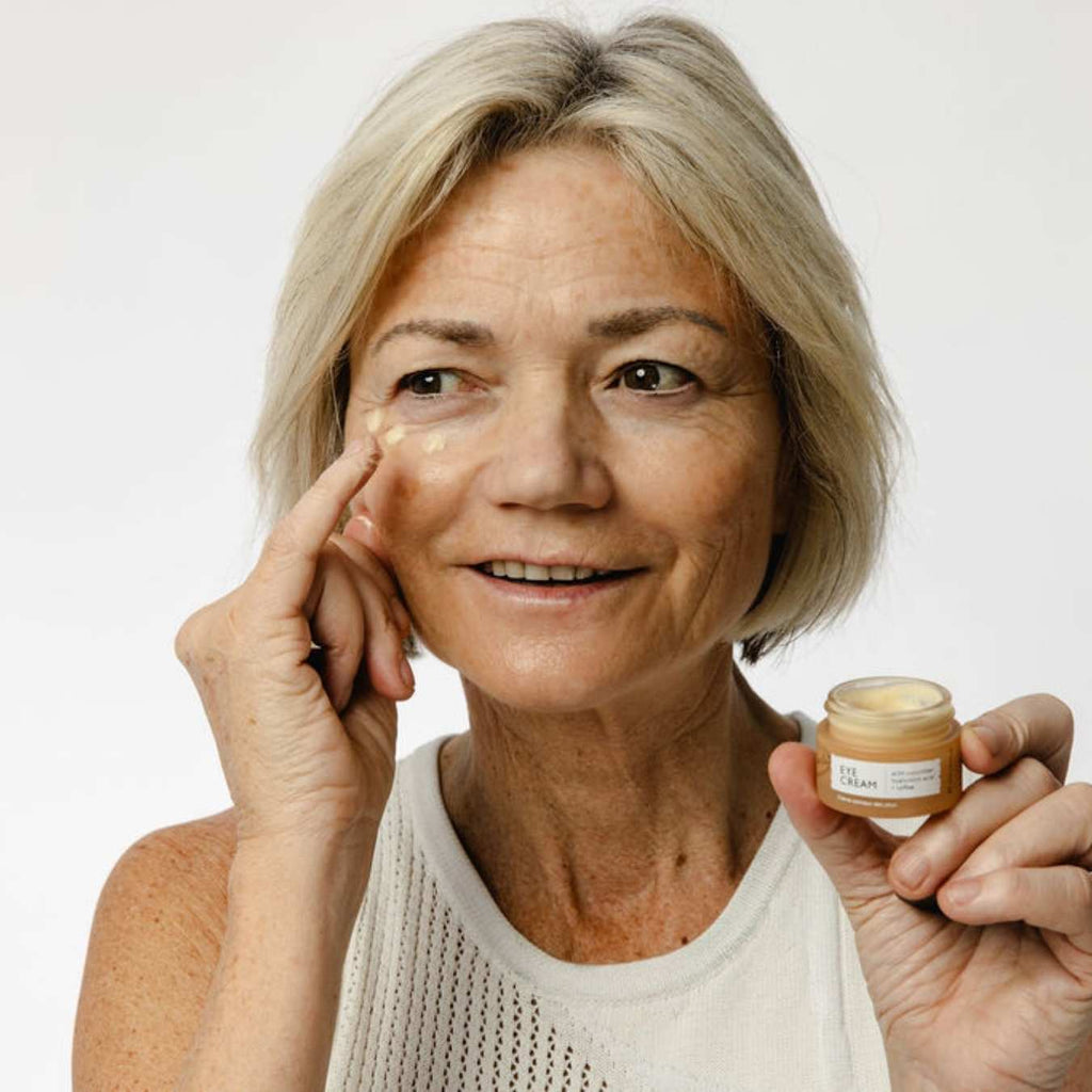 Woman smiling while holding the eye cream jar, skincare duo in hand