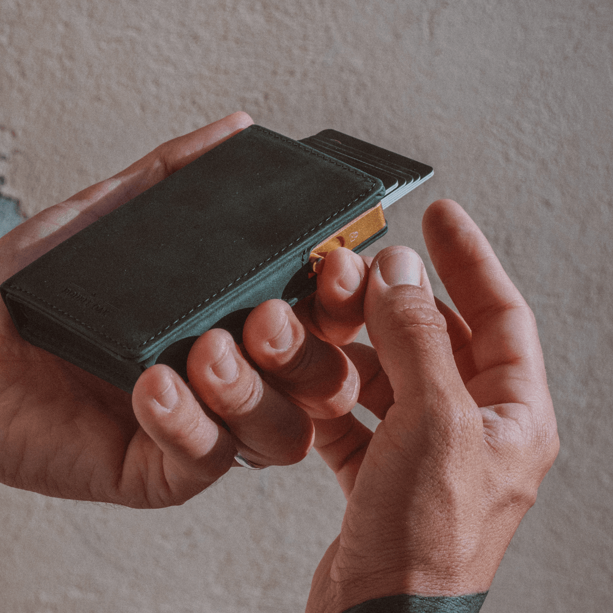 Black bifold wallet with teal interior, one card partly pulled out.