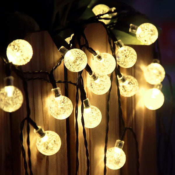 Outdoor solar fairy light string with round globe bulbs, warm white on a fence