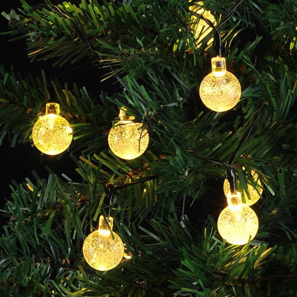 Solar fairy light string with round globe bulbs wrapped around Christmas tree