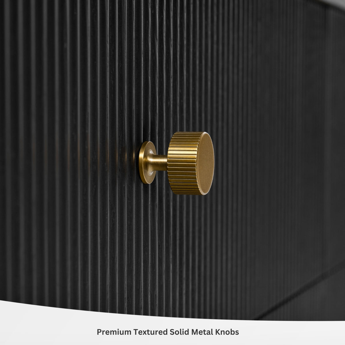 Gold round textured metal knob on dark fluted black bath vanity cabinet