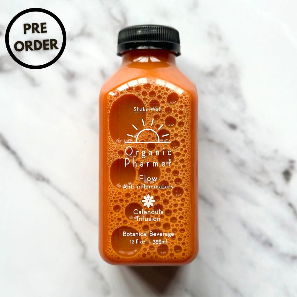 Organic Flow botanical beverage bottle, orange liquid, black cap, front label visible.