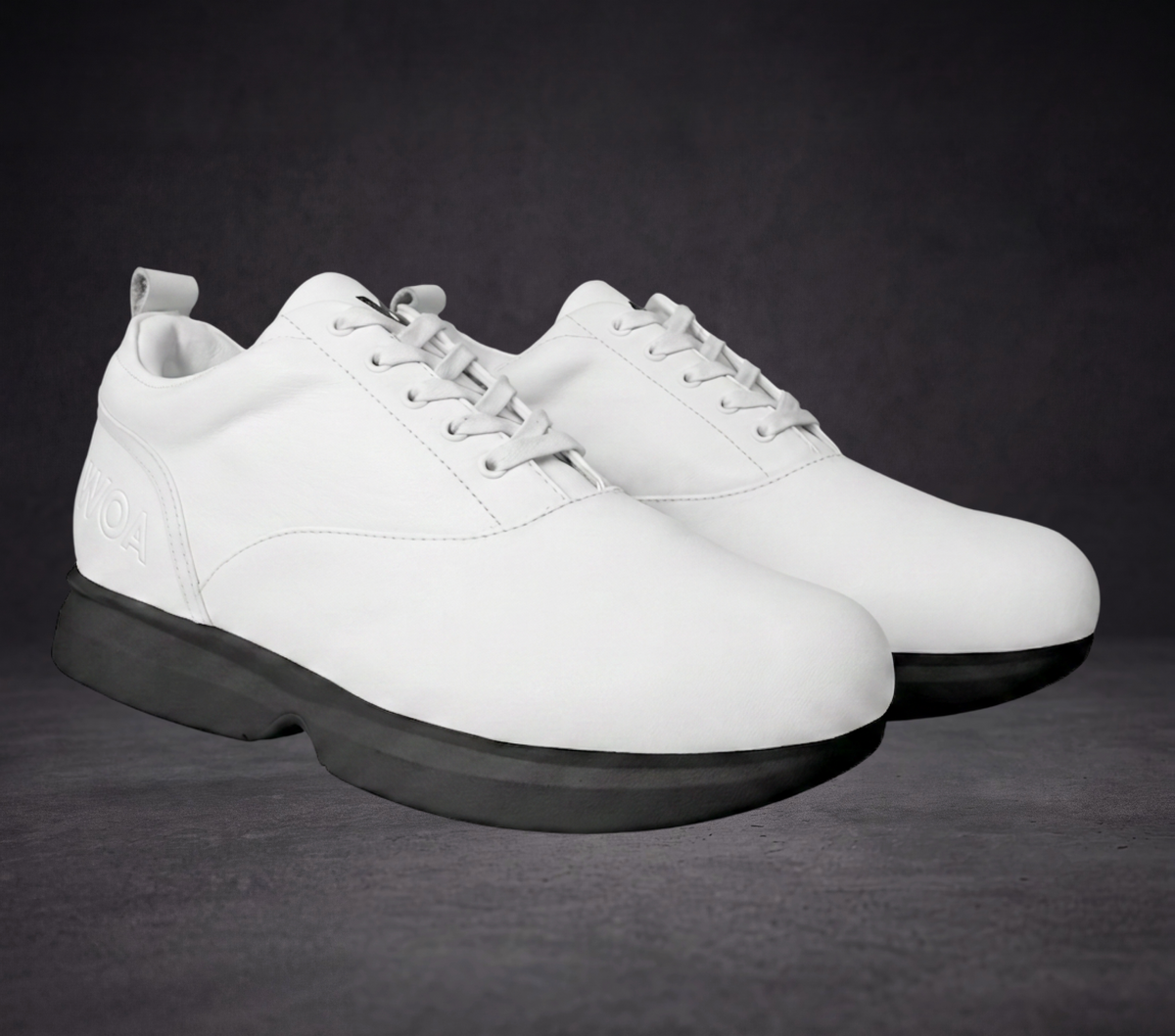Pair of white WOA sneakers with lace-up fronts and black platform soles