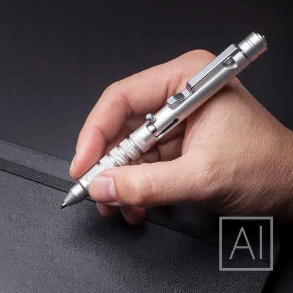 Silver bolt-action EDC pen held in hand, clip and tip visible