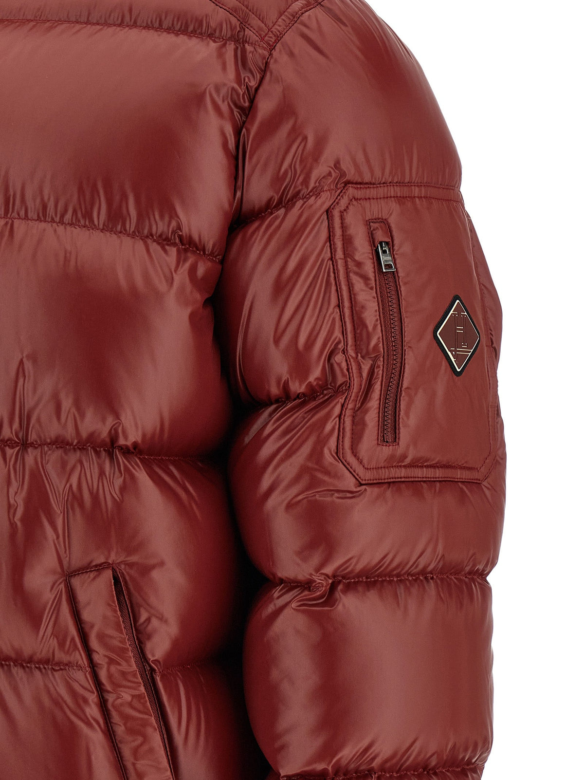 Men's Herno burgundy puffer jacket close-up: chest logo patch and zippered pocket.