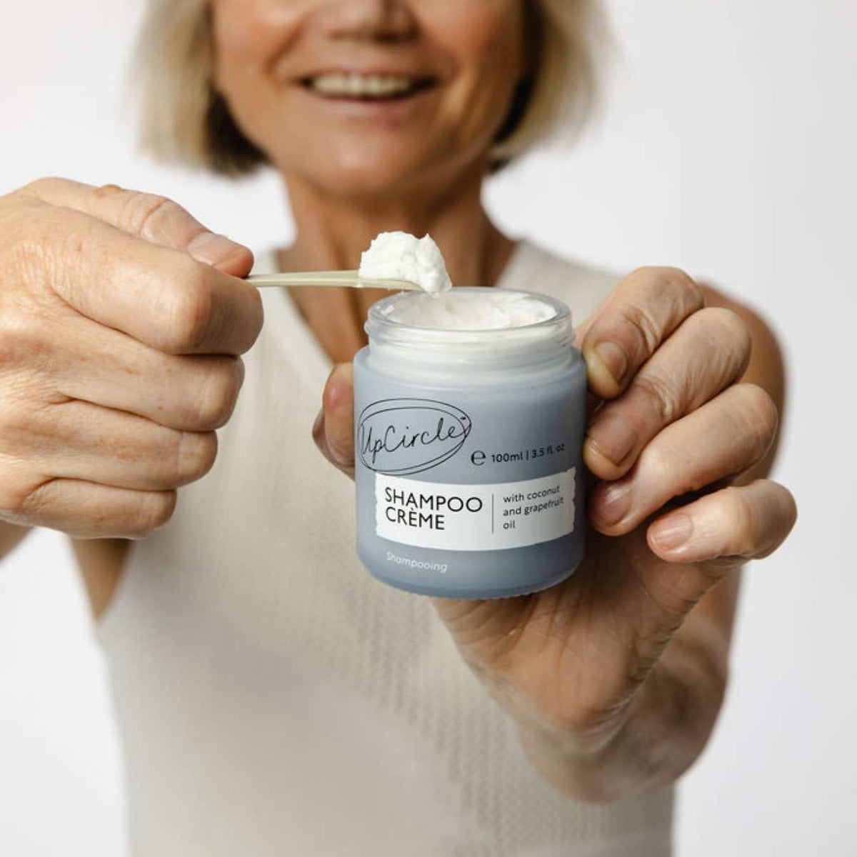 UpCircle shampoo creme jar with spoon holding white cream.