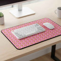 Pink cat-pattern desk mat with black border and rounded corners on a desk