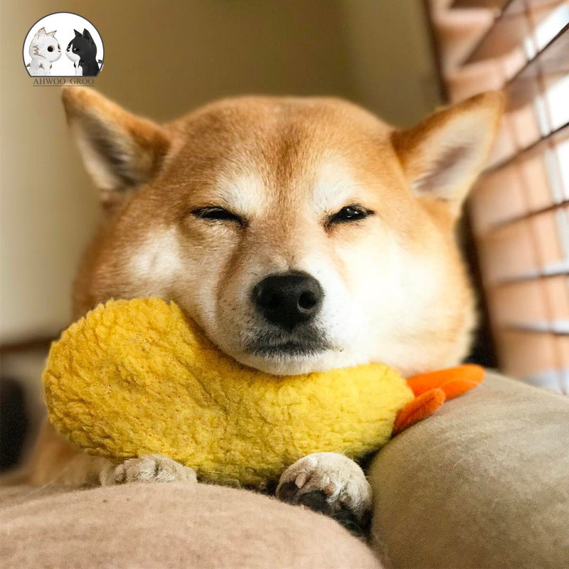 Shiba Inu hugging yellow shrimp plush dog toy with orange tail