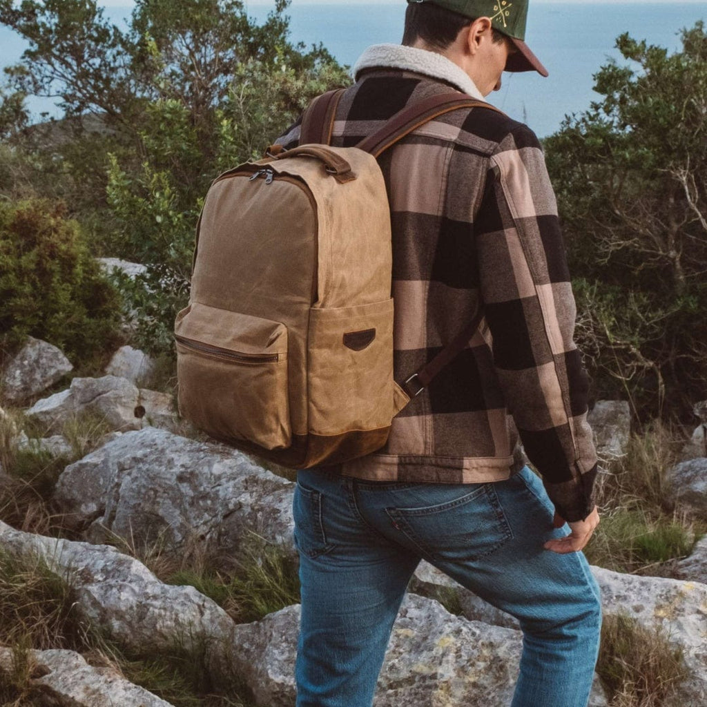 Tan canvas backpack with brown leather trim, worn on a person