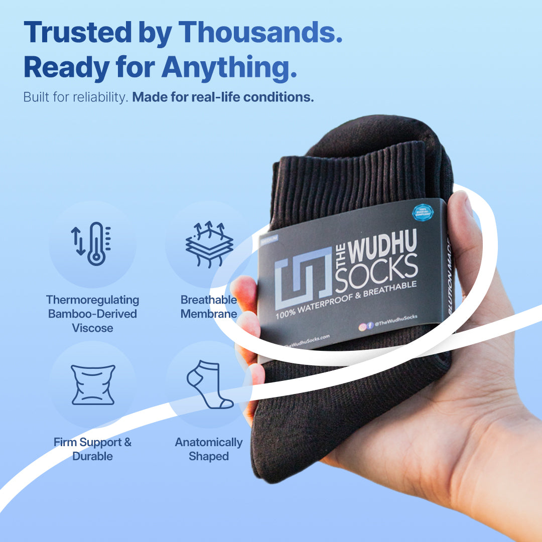 Black crew socks with blue logo patch held in a hand