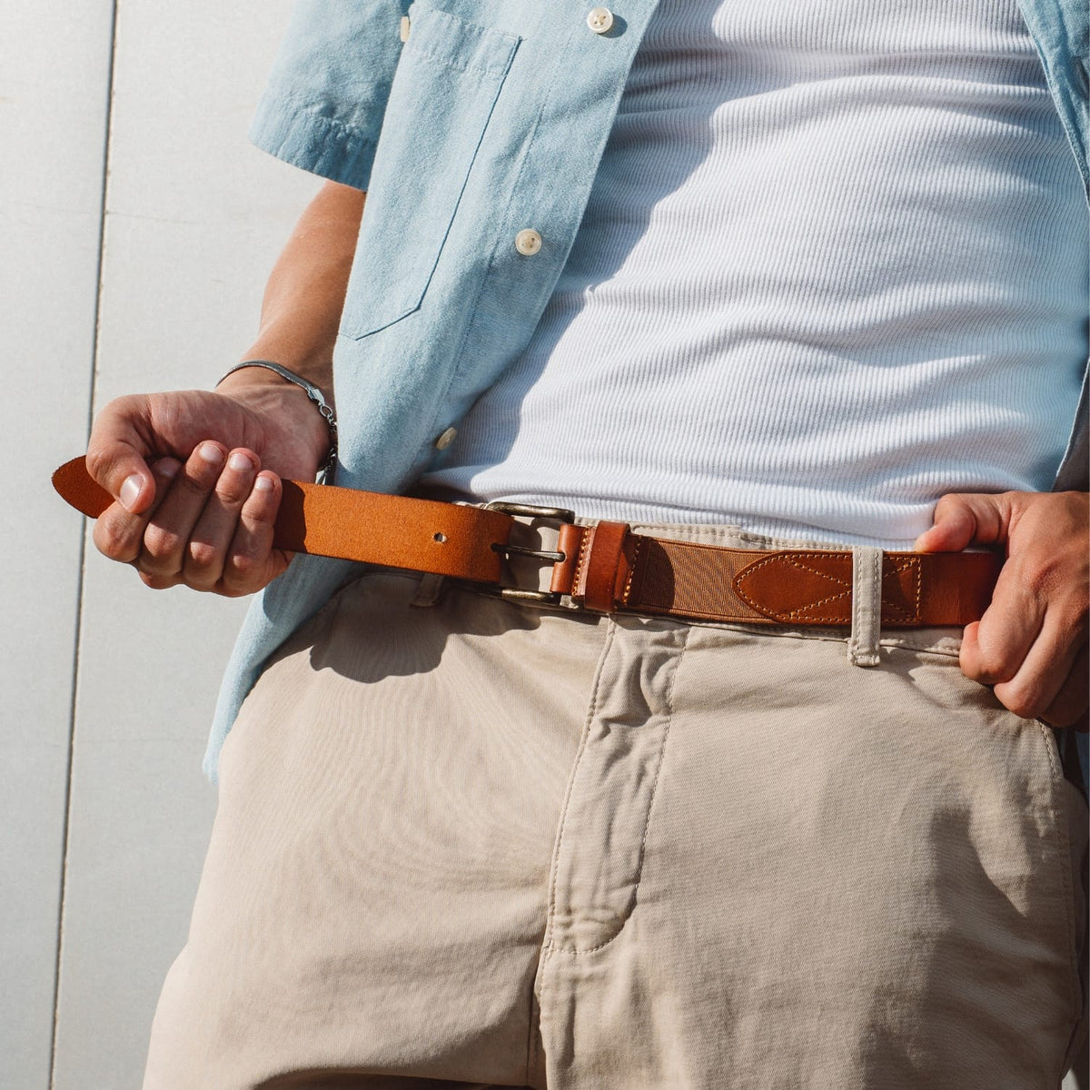 Brown leather stretch belt with metal buckle and keeper, worn at waist