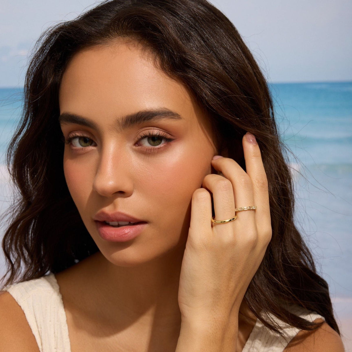 Gold-tone ring with rectangular clear stones on finger, model close-up