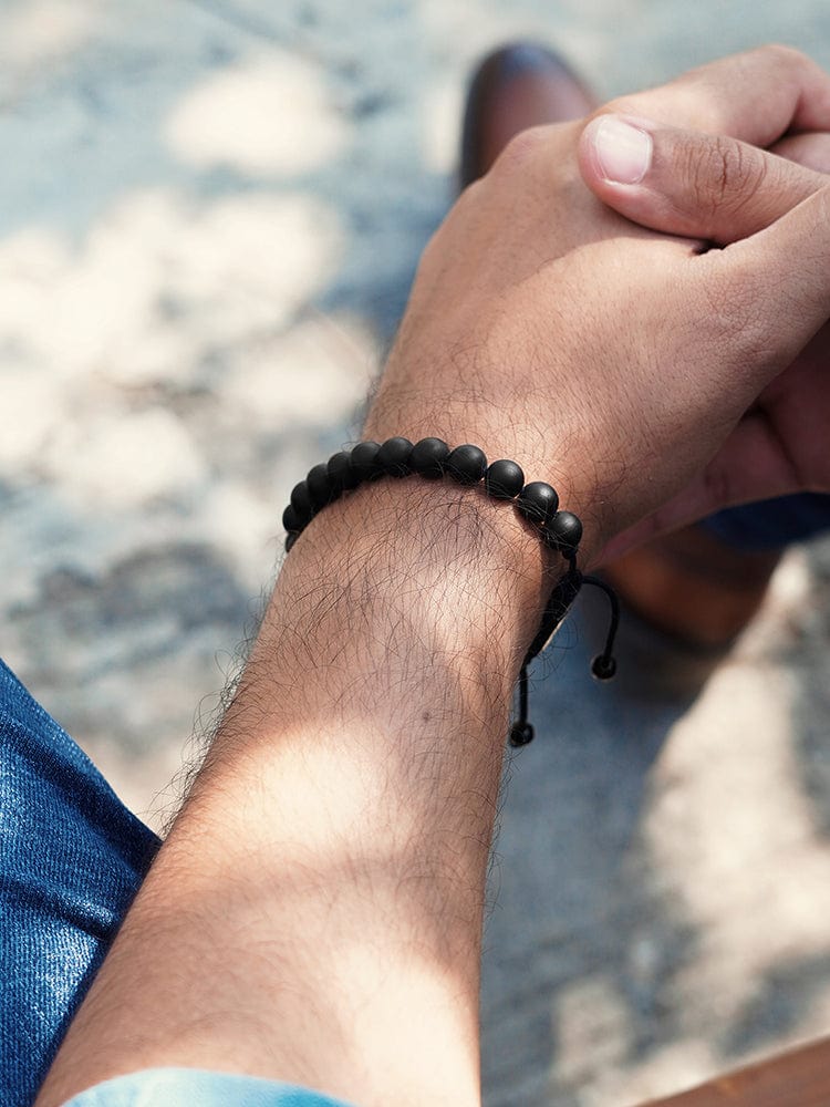 Black beaded bracelet on wrist with knotted cord and round bead strands