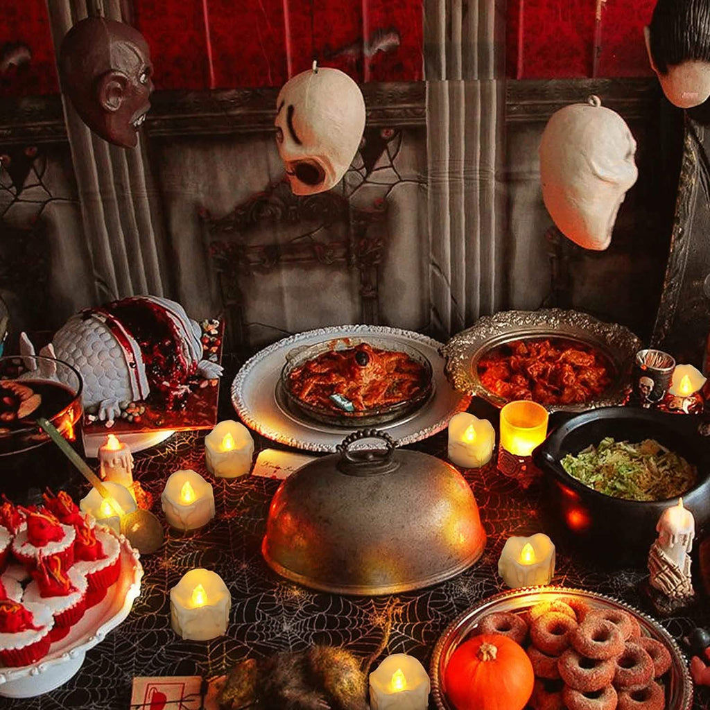 White LED candles with glowing flames among Halloween table decor