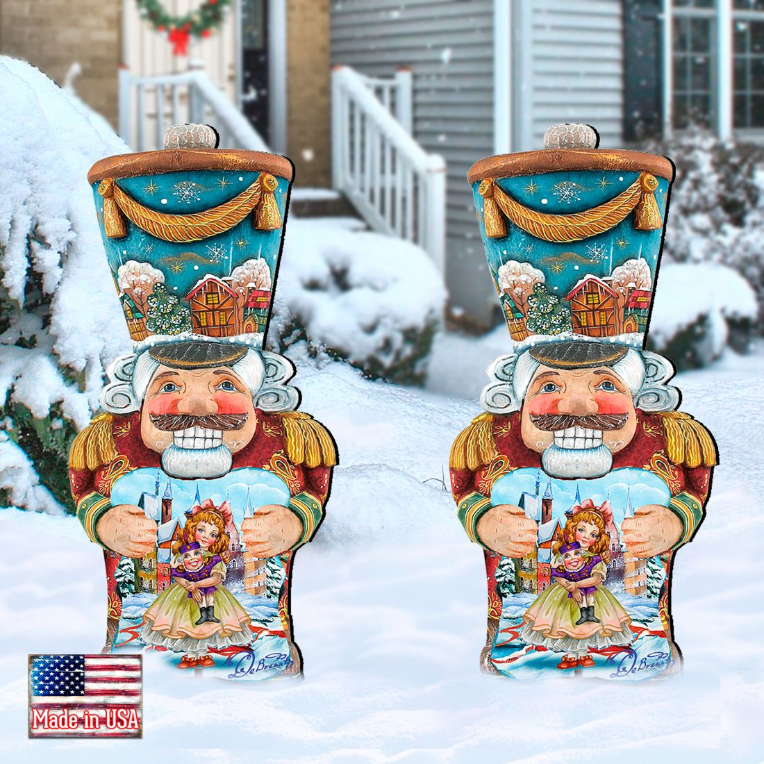 Two painted blue nutcracker yard decorations with white beards, holding dolls, in snow