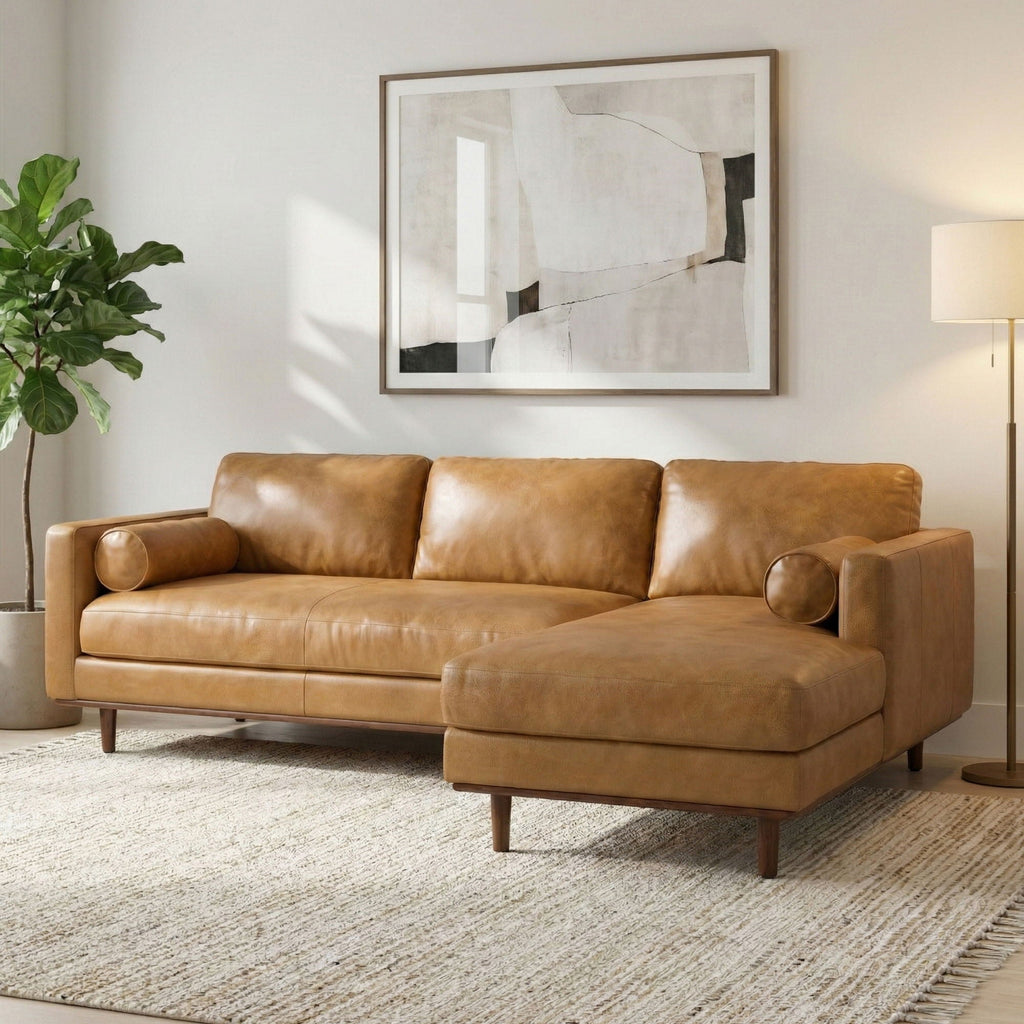 Tan leather sectional sofa with chaise extension, rolled accent pillow, and wooden legs