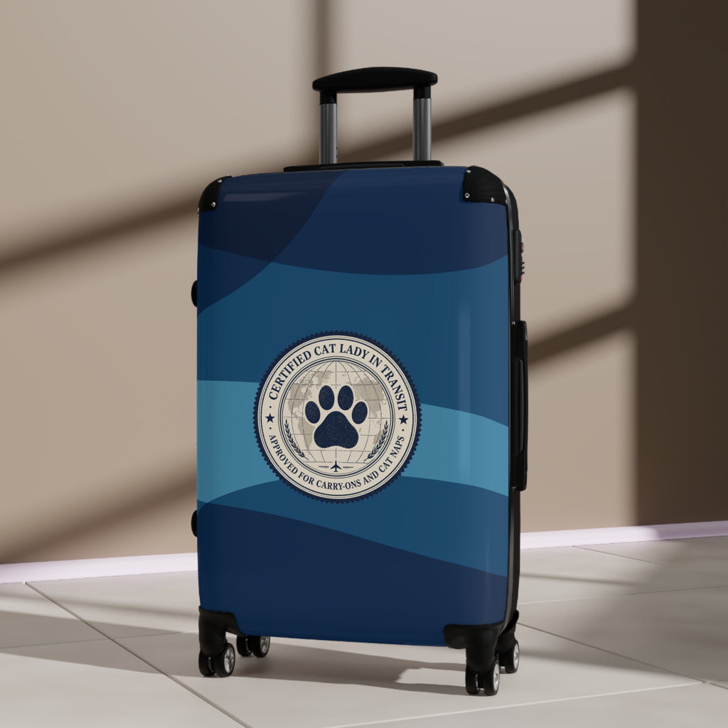 Hard-shell suitcase, blue with cat paw emblem on front and four spinner wheels