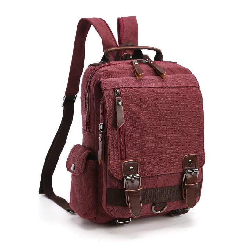 Burgundy canvas backpack with top handle, front flap pocket, and adjustable shoulder strap