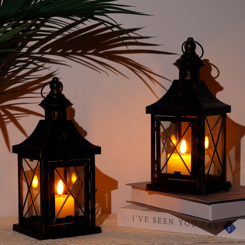 Two black metal hanging candle lanterns with glass panels and finial top handles