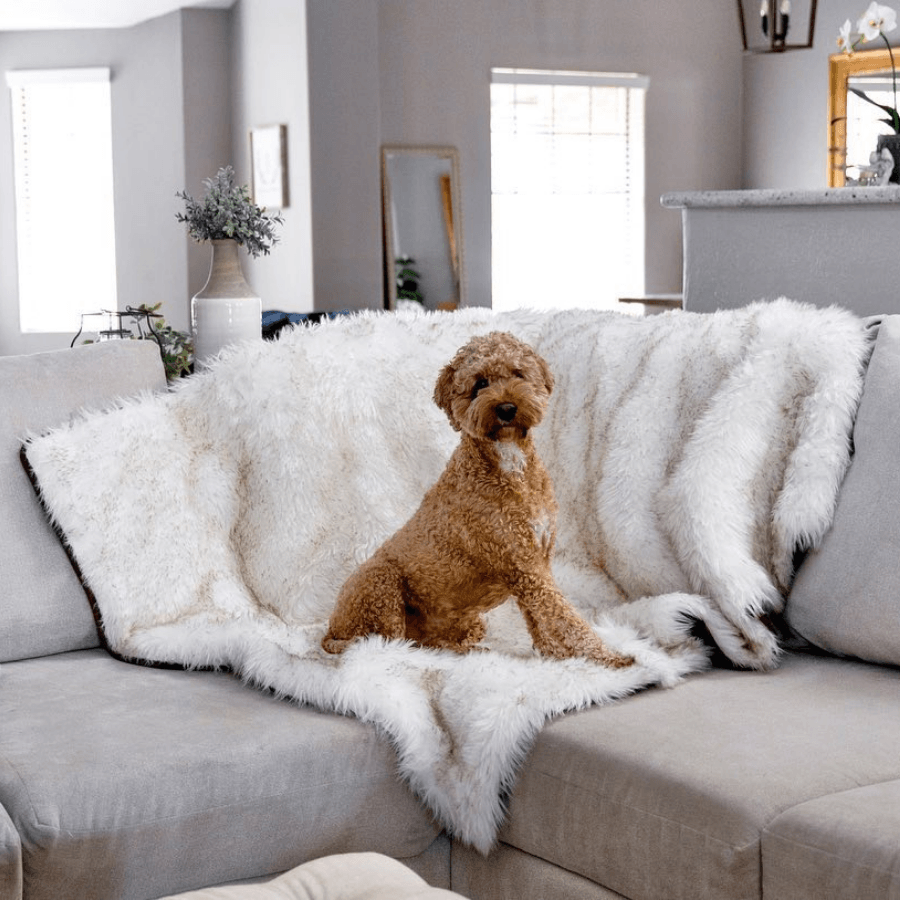 White faux-fur waterproof throw blanket draped over a grey sectional couch