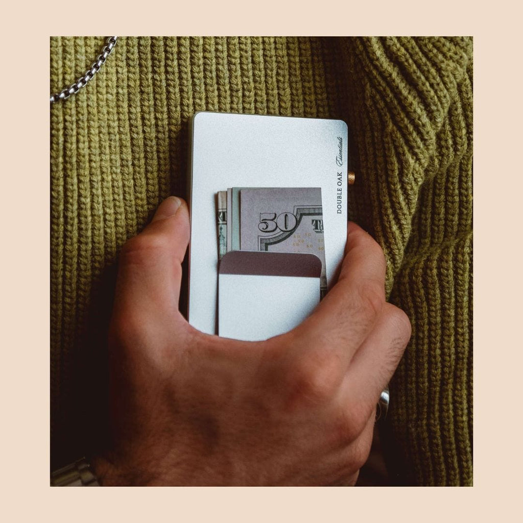 Light gray pop-up cardholder open with cash bills inserted, held in hand.