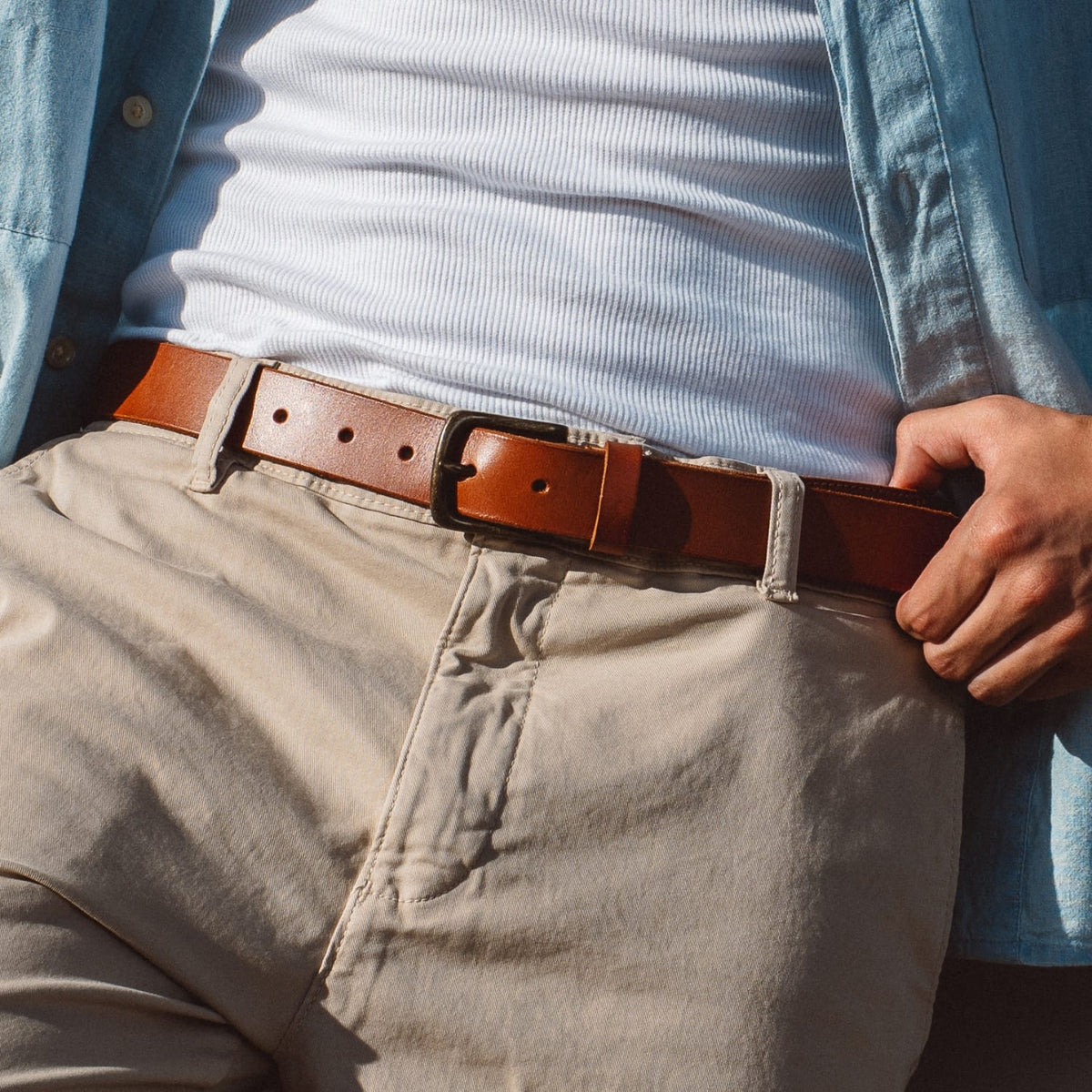 Brown leather belt with silver buckle worn with khaki pants