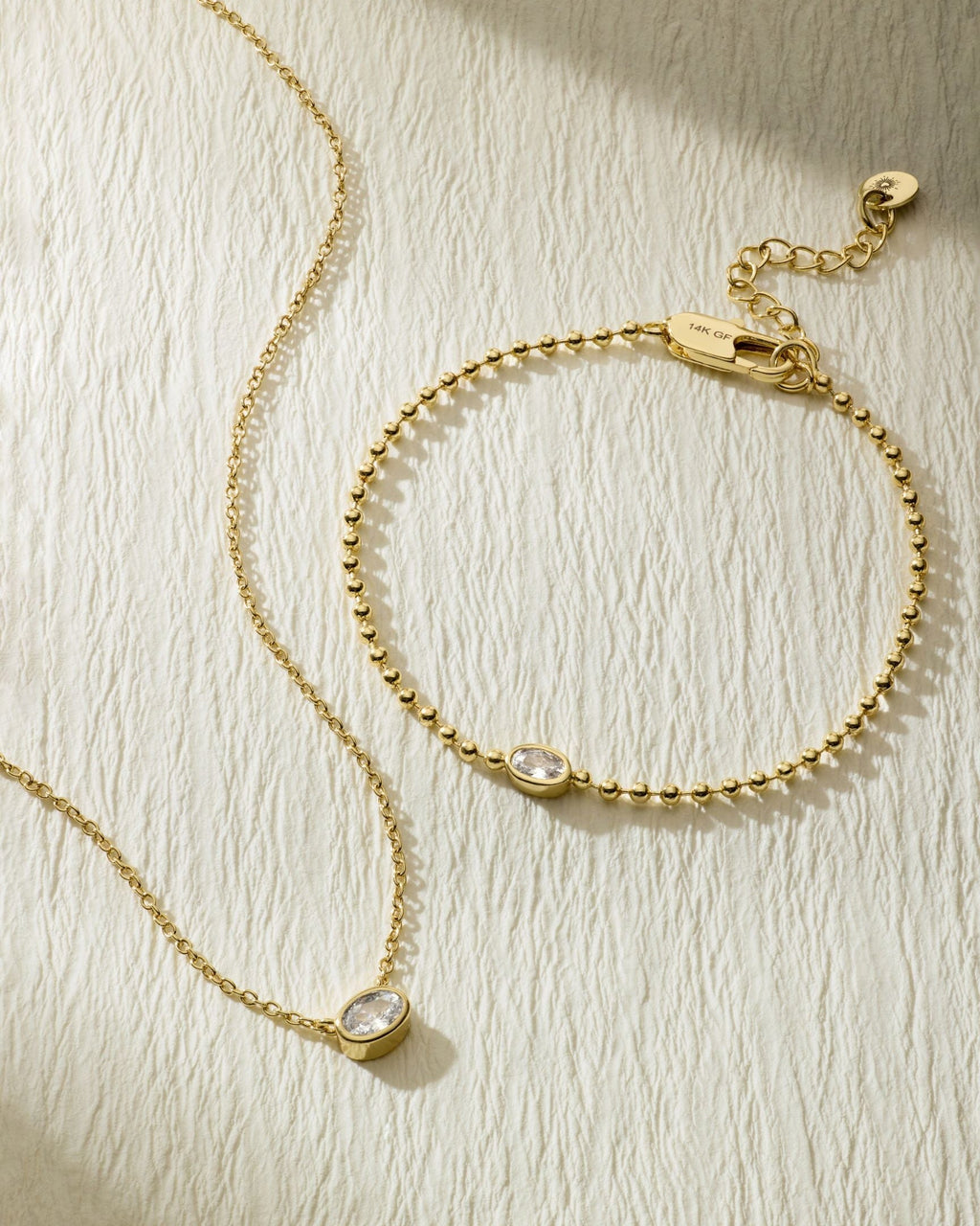 Gold-tone beaded bracelet with oval stone pendant and clasp; flat lay