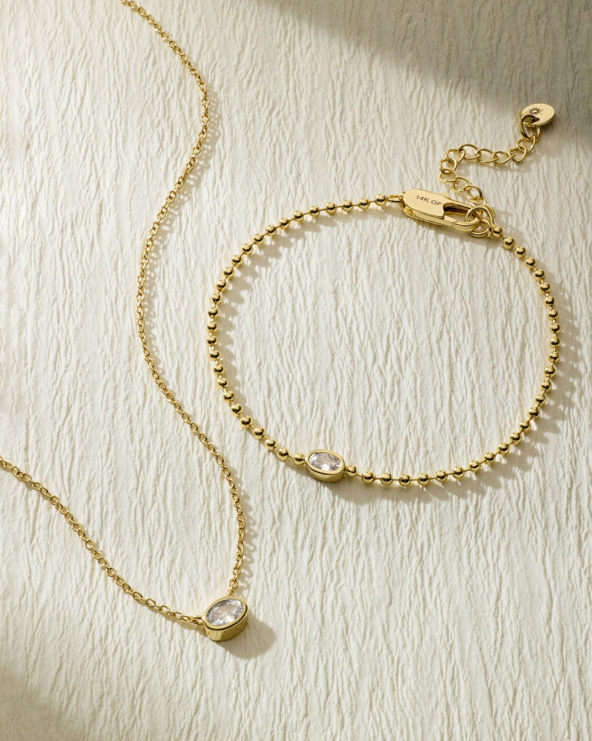 Gold-tone beaded bracelet with oval stone pendant and clasp; flat lay