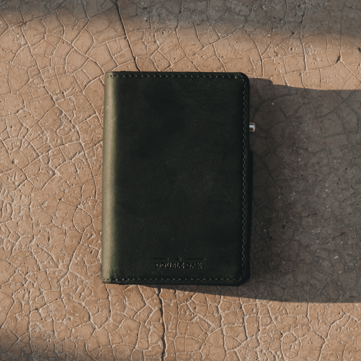 Dark green leather bifold wallet with stitched border and front logo