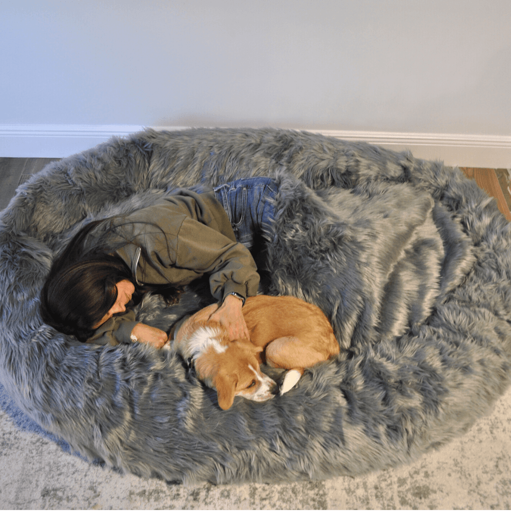 Charcoal grey faux fur dog bed in close-up with sleeping dogs nestled inside