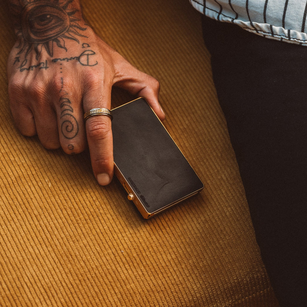 Mod wallet with black card window and gold-tone frame, held in a hand